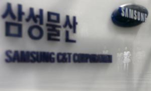 Employees are reflected on a logo of Samsung C&T Corp at the company's headquarters in Seoul